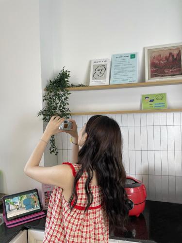 a woman in a kitchen holding a plant on a shelf at Corgi House Danang in Danang