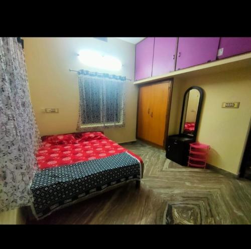a room with a bed with red pillows and a mirror at Divya Homestay in Udupi
