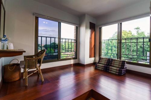 a living room with a table and chairs and large windows at TREETOP - Fong Lee CC Lampang Walking Street in Lampang