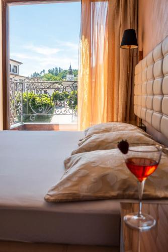 a bed with a glass of wine and a window at Enika Hotel in Tryavna