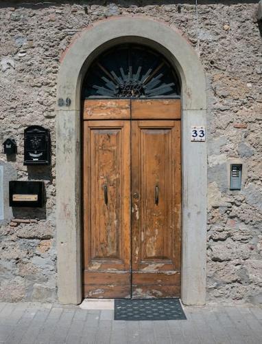 a large wooden door in a stone building at Casa del borgo antico in Poggibonsi