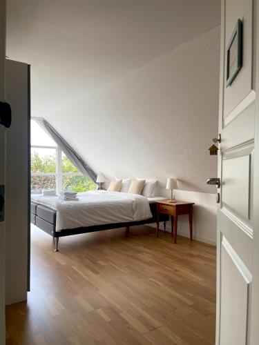 a white bedroom with a bed and a table at Kirsebærkroen - The Inn Between in Præstø