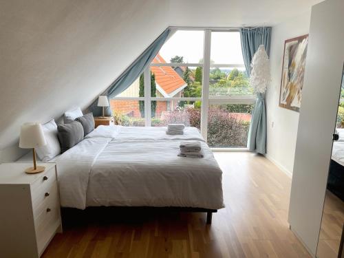a bedroom with a bed and a large window at Kirsebærkroen - The Inn Between in Præstø
