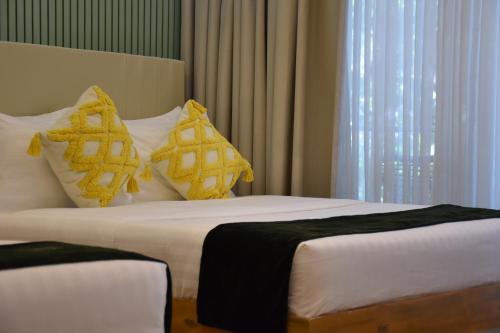 a hotel room with two beds with yellow pillows at Don Arc White Beach Resort in Initao
