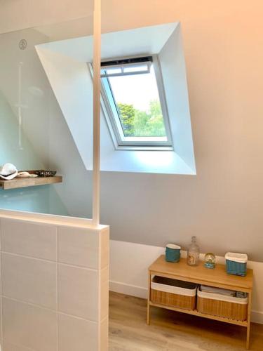 Cette chambre mansardée dispose d'une fenêtre et d'une table. dans l'établissement Un verger en bord de mer, à Locmariaquer