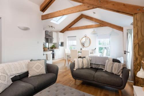 a living room with two couches and a kitchen at Sennen Surf Loft, Sennen in Sennen