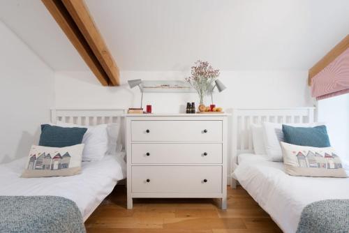 two twin beds in a room with a dresser at Sennen Surf Loft, Sennen in Sennen