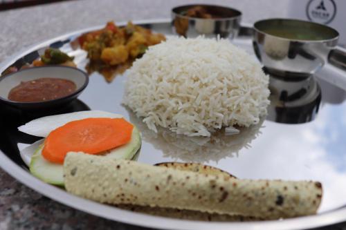 a plate of food with rice and vegetables on a table at Suryachaur Nature Retreat in Thāpāgāon