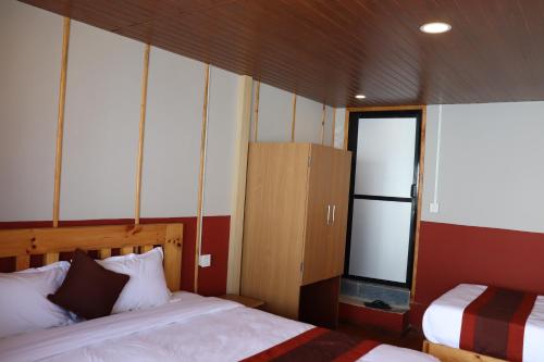 a bedroom with two beds and a cabinet in it at Suryachaur Nature Retreat in Thāpāgāon