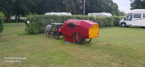 a red and yellow carriage parked in a field at Charlottsborgs Camping och Vandrarhem in Kristianstad