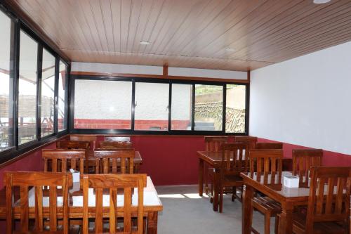 a restaurant with wooden tables and chairs and windows at Suryachaur Nature Retreat in Thāpāgāon