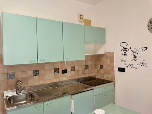 a kitchen with blue cabinets and a sink and a refrigerator at Mare e natura a Nisportino in Casa Castagno