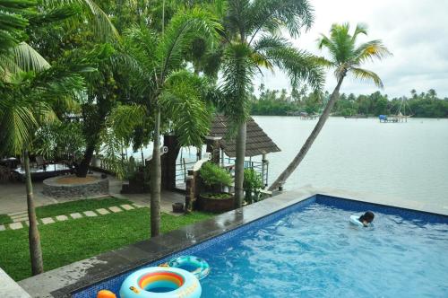 a person in a swimming pool next to a body of water at Ambadi's villa -Lake view resort in Pallipuram