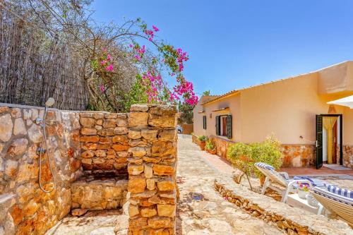 a stone wall next to a house with a bench at Can Juanito by dracmallorca in Cala Llombards