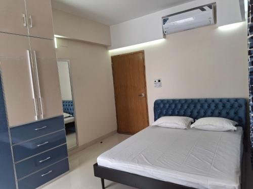 a bedroom with a bed with a blue headboard and a mirror at Elegant Secured Family Apartment with Open Space in Dhaka