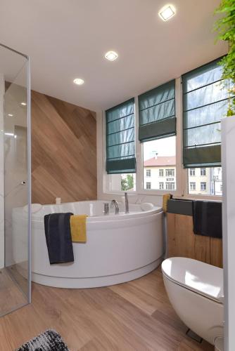 a large bathroom with a tub and a toilet andwindows at Urban Eden - LUX & STYLE, 2-Bedroom, 2-Bathroom in Sofia