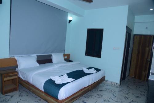 a bedroom with a large bed with white towels on it at Hotel Gridhakuta International in Rājgīr
