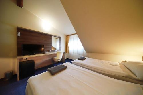 a hotel room with two beds and a flat screen tv at Pension Harmonie -self check-in in Kolín