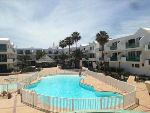 a large swimming pool in front of some apartments at Ground floor apartment with pool, next to the beach in Costa Teguise