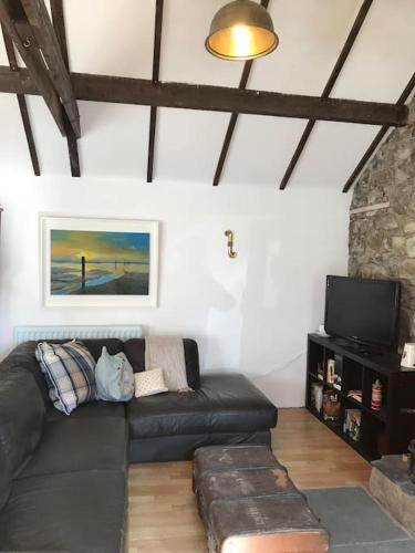 a living room with a black couch and a tv at Stone Wall Cottage in Castlewellan