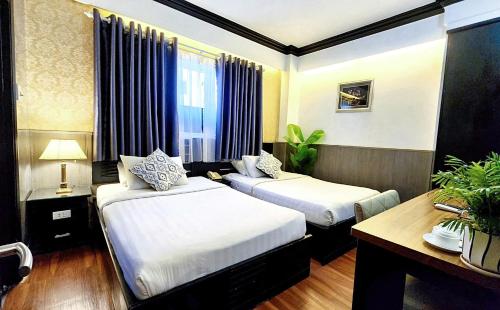 a hotel room with two beds and a desk at Rosa Hotel & Spa in Ho Chi Minh City