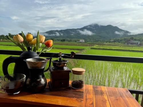 a wooden table with a vase of flowers on it at KheangKhangKhao เคียงข้างเขา ปัว-สกาด in Pua