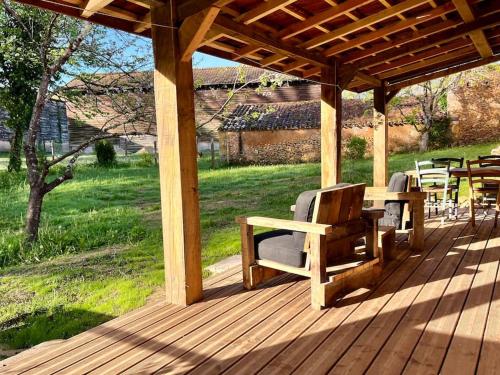 a wooden deck with chairs and a table on it at gîte sivade - vue épique - grand jardin clôturé in Capdrot