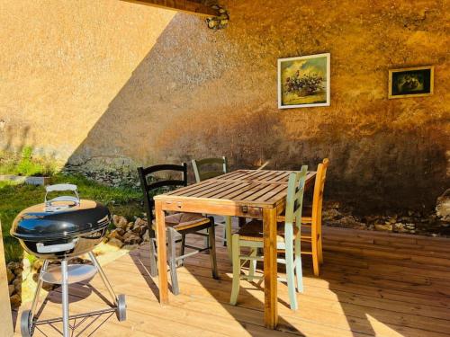 a grill and a wooden table and chairs on a patio at gîte sivade - vue épique - grand jardin clôturé in Capdrot