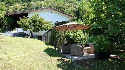 a patio with an umbrella and chairs in a yard at BBPrimavera in Purasca