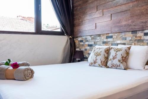 a bedroom with a white bed with a brick wall at Enika Hotel in Tryavna