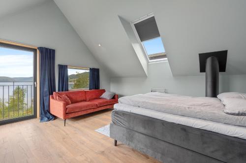 a bedroom with a bed and a red couch at Modern house by the Fjord in Sandane, Nordfjord. in Sandane