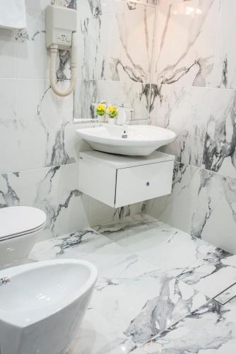 a white marble bathroom with a sink and a toilet at Enika Hotel in Tryavna