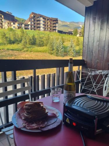 - une table avec une assiette de nourriture et une bouteille de vin dans l'établissement LE BOIS DES COQS 1 Studio 2 à 3p Serre Chevalier 1350m avec balcon 5m2 parking et casier à ski, à Saint-Chaffrey