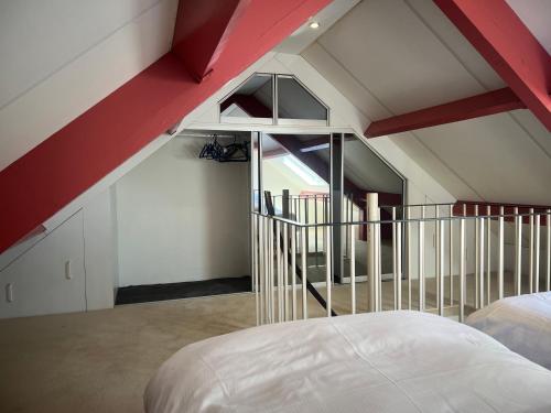 an attic bedroom with a red and white ceiling at Anda in Zandvoort