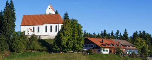 a white church with a red roof on a hill at Panoramagasthof auf dem Auerberg in Bernbeuren