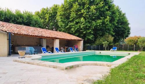 une piscine avec des chaises bleues et une maison dans l'établissement Mas Les Fabrys au coeur du Luberon, à Bonnieux