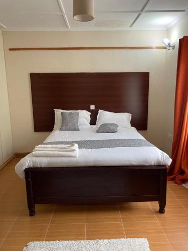 a bedroom with a large bed with a wooden headboard at Airport View Homes in Eldoret
