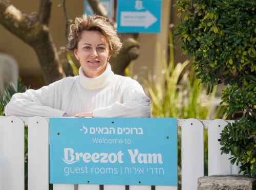 a woman standing behind a fence with a sign at Breezot Yam in Nahariyya