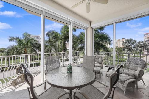 a balcony with a table and chairs and windows at Peaceful condo with pool and steps to South Beach in Marco Island