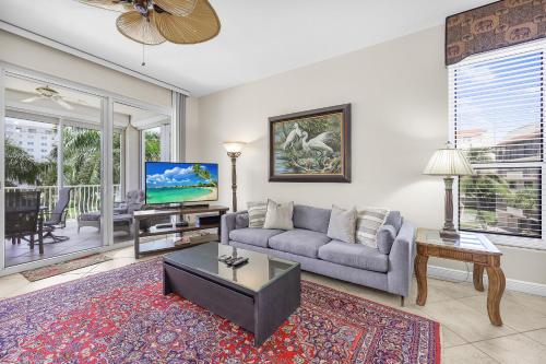 a living room with a couch and a tv at Peaceful condo with pool and steps to South Beach in Marco Island