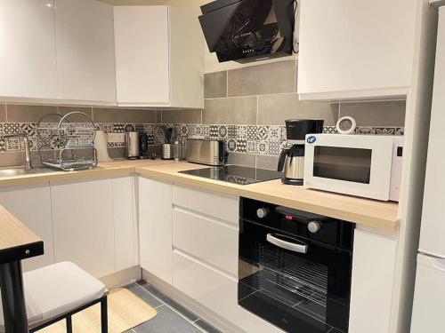 La cuisine est équipée de placards blancs et d'un four micro-ondes. dans l'établissement Petite maison sympathique, à Saint-Malo