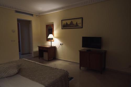 a bedroom with a bed and a tv and a lamp at Alhambra Thalasso in Hammamet