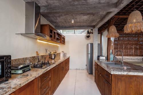 Una cocina con gabinetes de madera y un refrigerador de acero inoxidable. en Dolce Vita Nusa Penida, en Nusa Penida