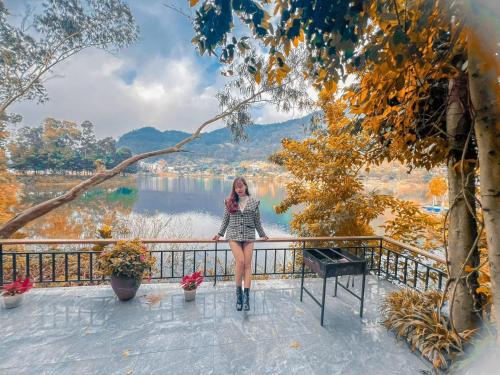 a woman standing on a balcony overlooking a lake at Nhà Ven Hồ Đồng Đò, Minh Trí, Sóc Sơn, Hà Nội in Hanoi