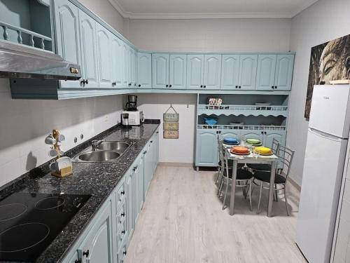 Una cocina con gabinetes azules y una mesa con sillas. en La Casa de Aba, en Telde