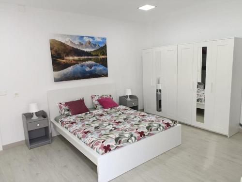 a white bedroom with a bed and a painting on the wall at La Casa de Aba in Telde
