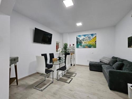 Una sala de estar con un sofá, una mesa y sillas. en La Casa de Aba, en Telde