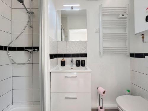 une salle de bain blanche avec un lavabo et un miroir dans l'établissement Le cocon, studio de 30m2 avec jardin et parking privatifs près de paris et Disney, à Fontenay-sous-Bois