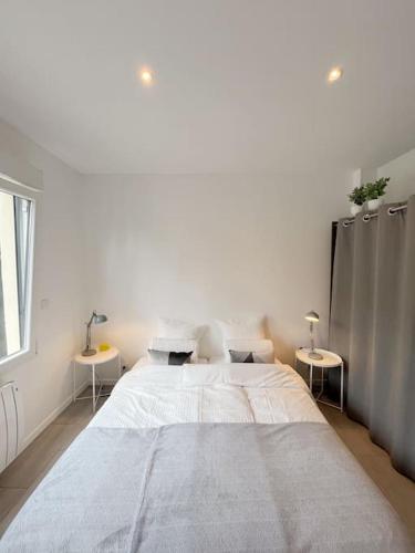 - une chambre blanche avec un grand lit et 2 tables dans l'établissement Le cocon, studio de 30m2 avec jardin et parking privatifs près de paris et Disney, à Fontenay-sous-Bois