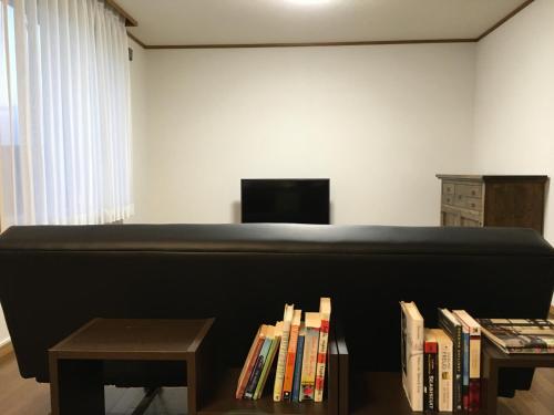 a living room with a couch and a row of books at Kaku in Furano